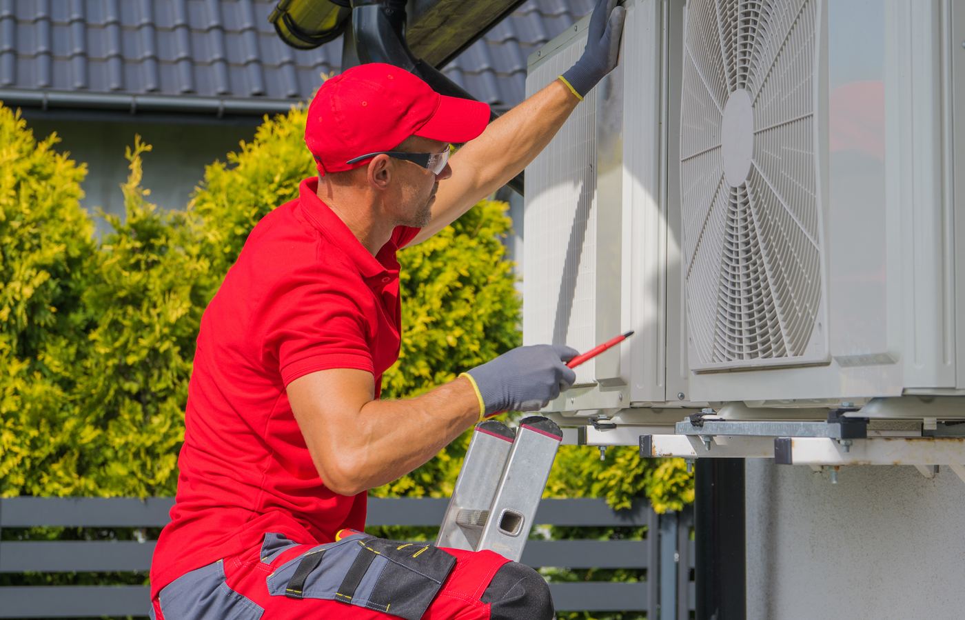 Techniker montiert ein Außengerät an der Hauswand