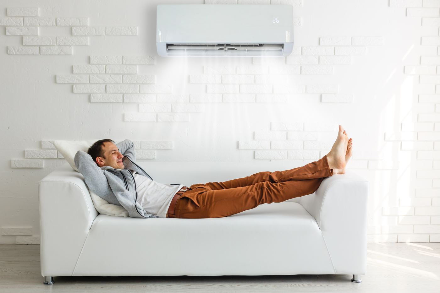 Mann entspannt auf dem Sofa unter einer Klimaanlage