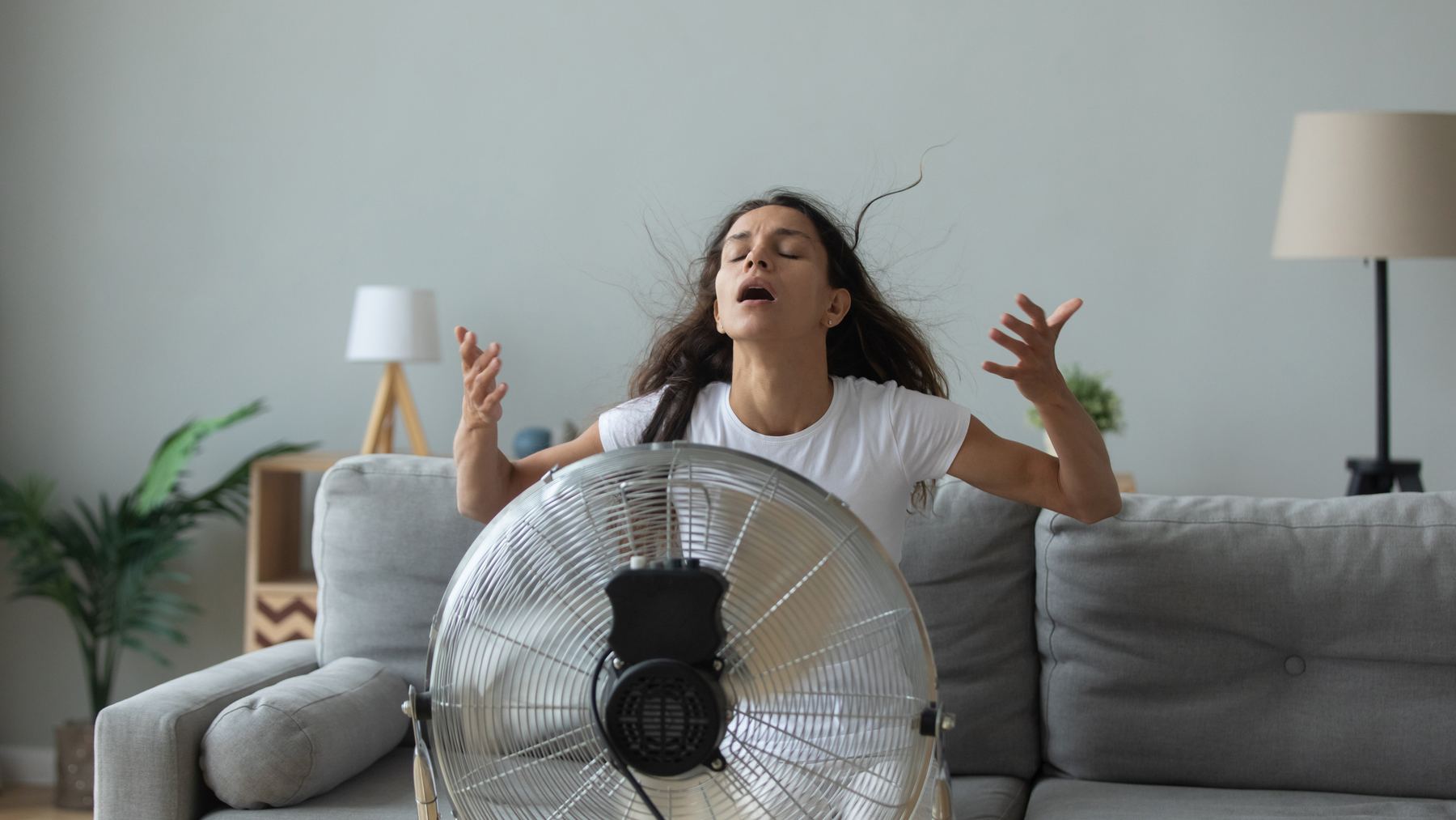 Frau vor einem Ventilator an einem heißen Tag